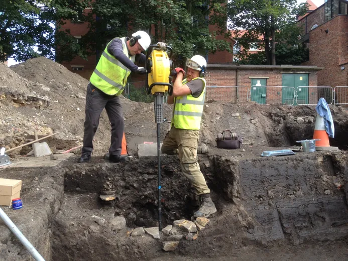 Two archaeologists using a handheld concussion borer to drill for palaeoenvironmental cores