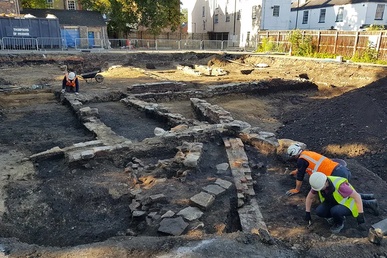 Archaeologists uncovering a series of walls on an urban excavation