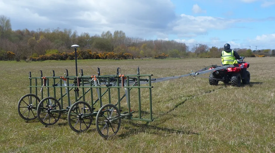 a quadbike pulling a cart-mounted geophysical survey system