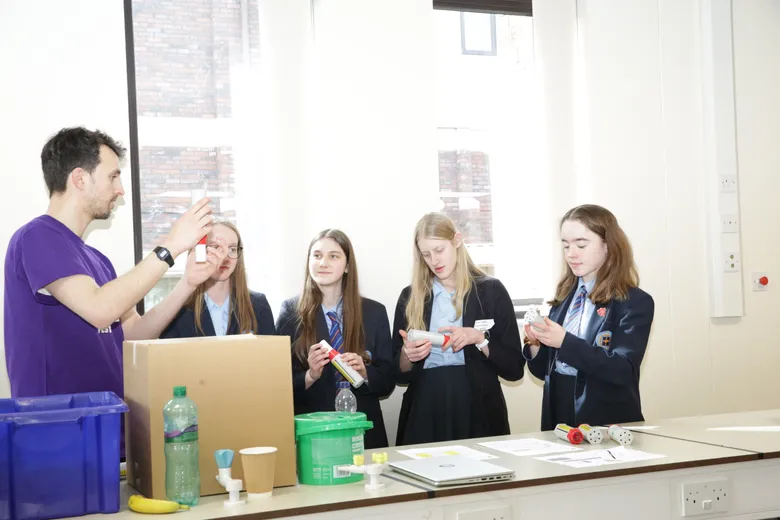 Four teenage students with long hair taking instruction from older tutor