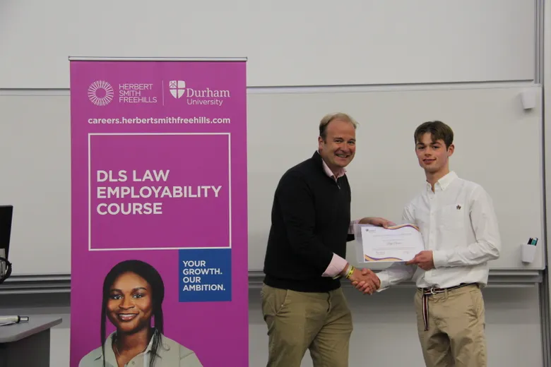 Michael Aherne, Partner, Herbert Smith Freehills presenting Benji Duncan, member of the first team to finish the course, with his 2023/24 Employability Completion of Course Certificate