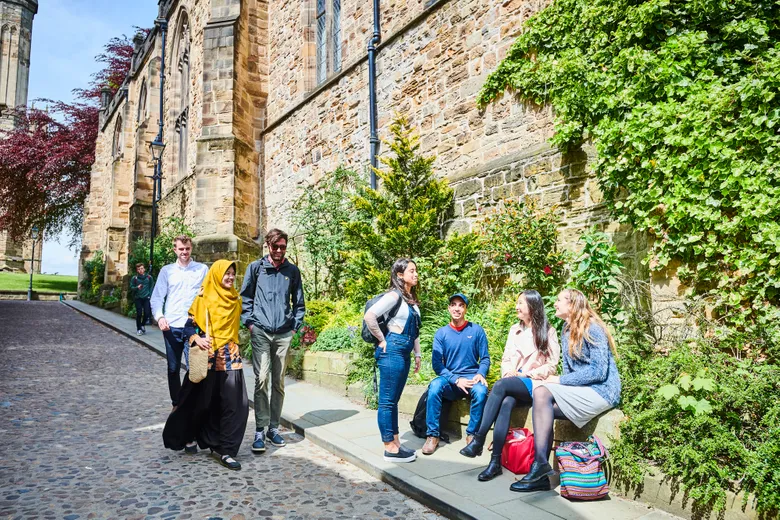 Students walking down Bow Lane by group sitting on wall