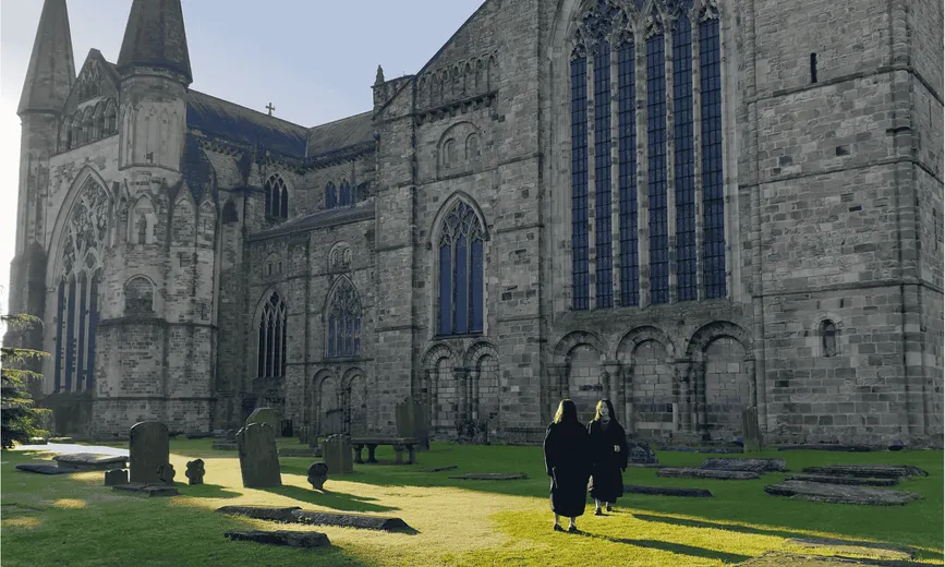 Two students taking photos in the grounds in front of Durham Cathedral