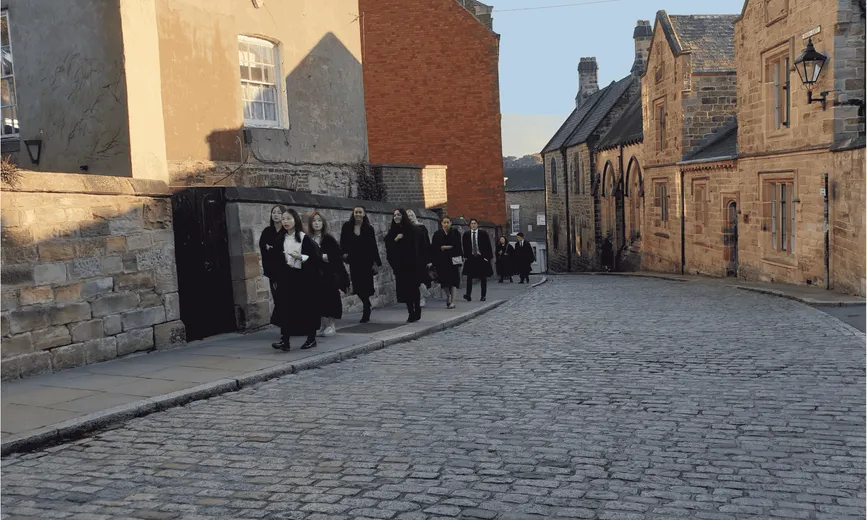 Students walking up a cobbled street in gowns