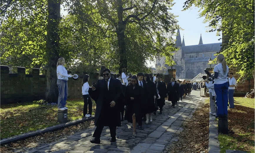 Students walking in robes with Durham Cathedral in the background