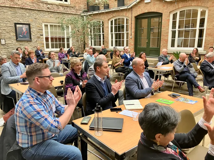 People sitting at tables clapping and smiling