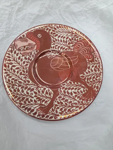 A decorative plate with stylised image of a bird and background of leaves