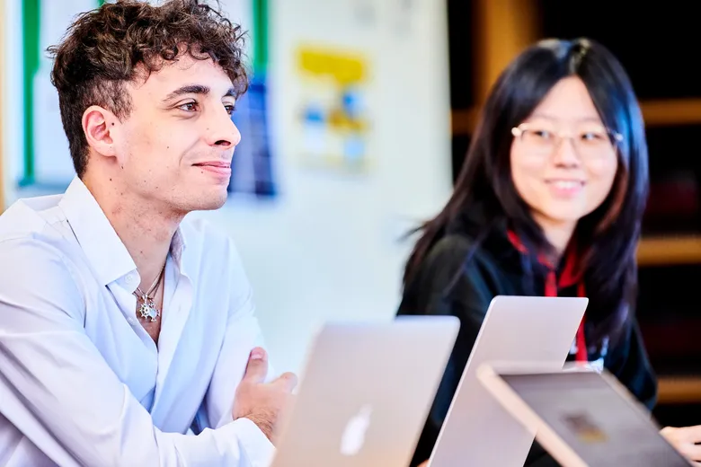 Two students with laptops smiling