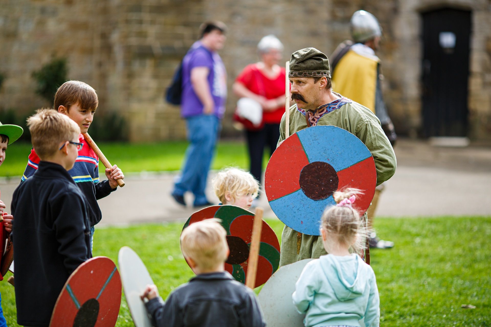 A coloured photograph of the courtyard at Durham Castle. At the front of the image of two medieval soldiers, in the background is a tent and the Tunstall Gallery of Durham Castle.