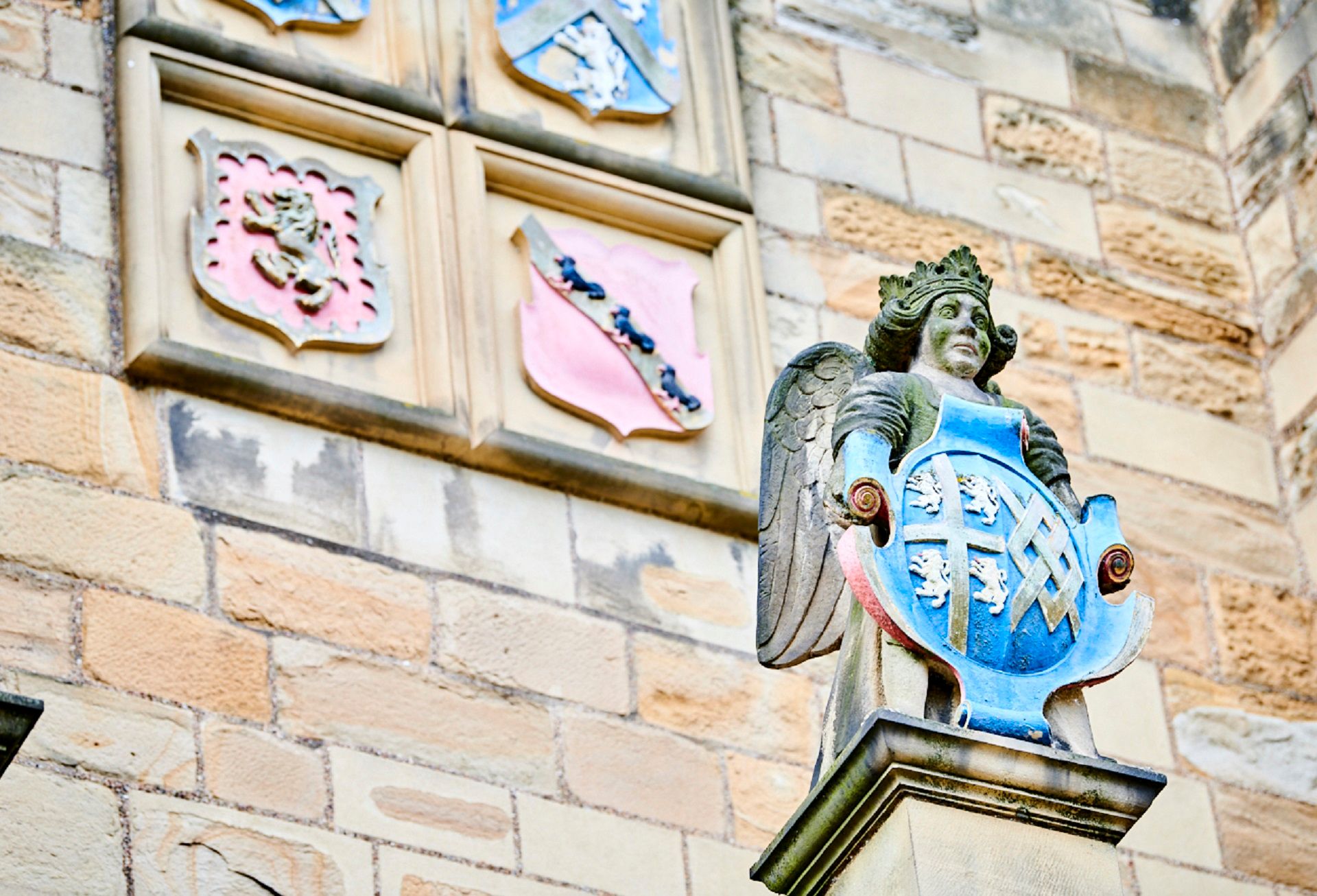 Above the entrance to the Great Hall. At the front is a crowned angel with the coat of arms of Bishop Cosin, with other coats of arms behind.