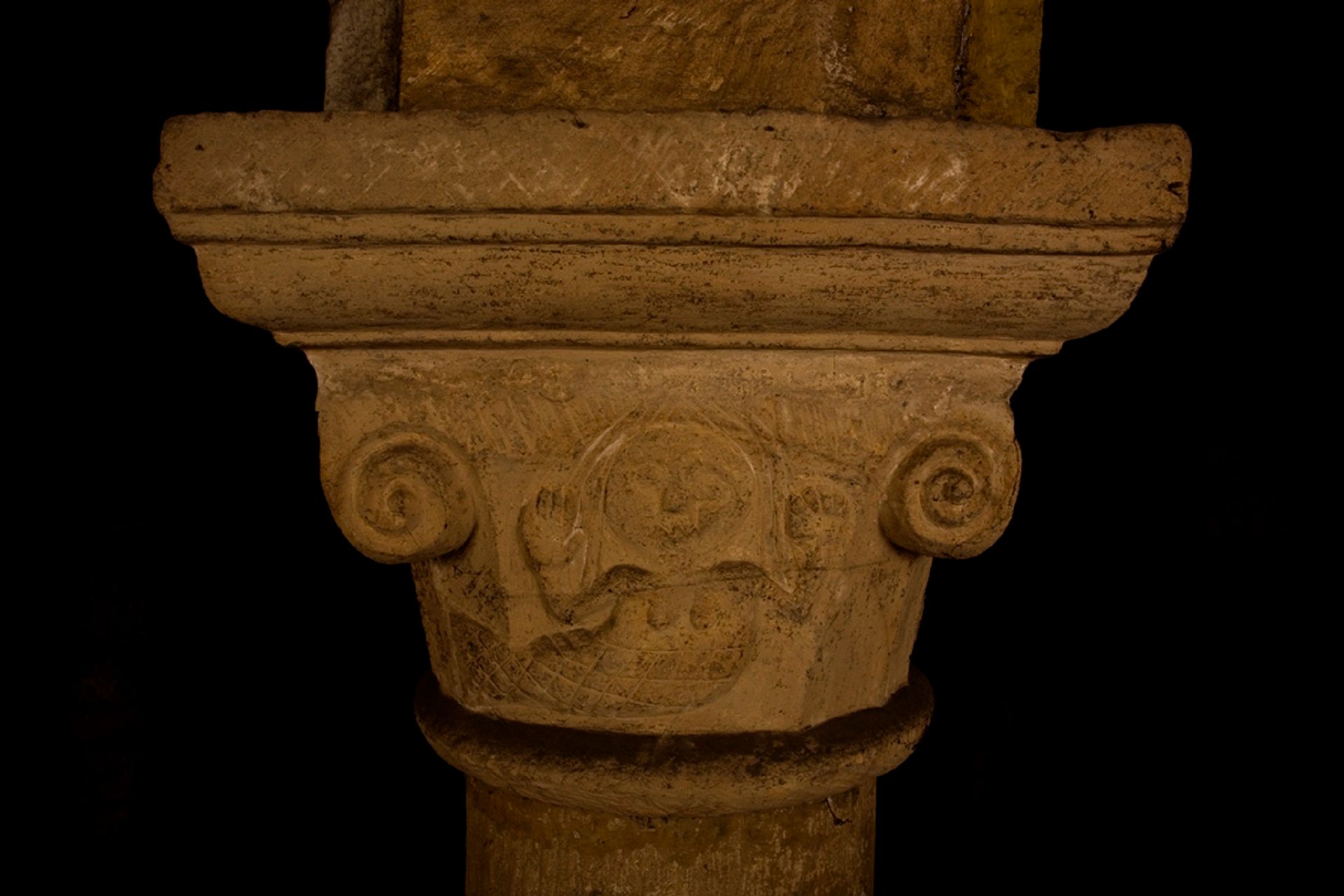 Photograph of the mermaid carving at the top of pillar in the Norman Chapel. She is depicted with raised hands.