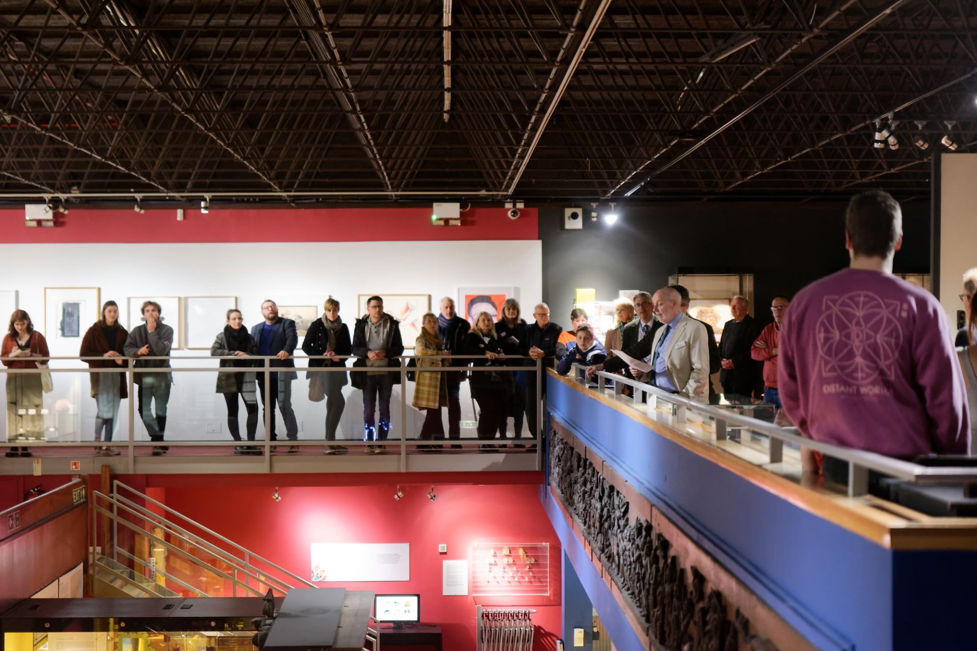Visitors to the exhibition standing on the mezzanine while listening to a speech.