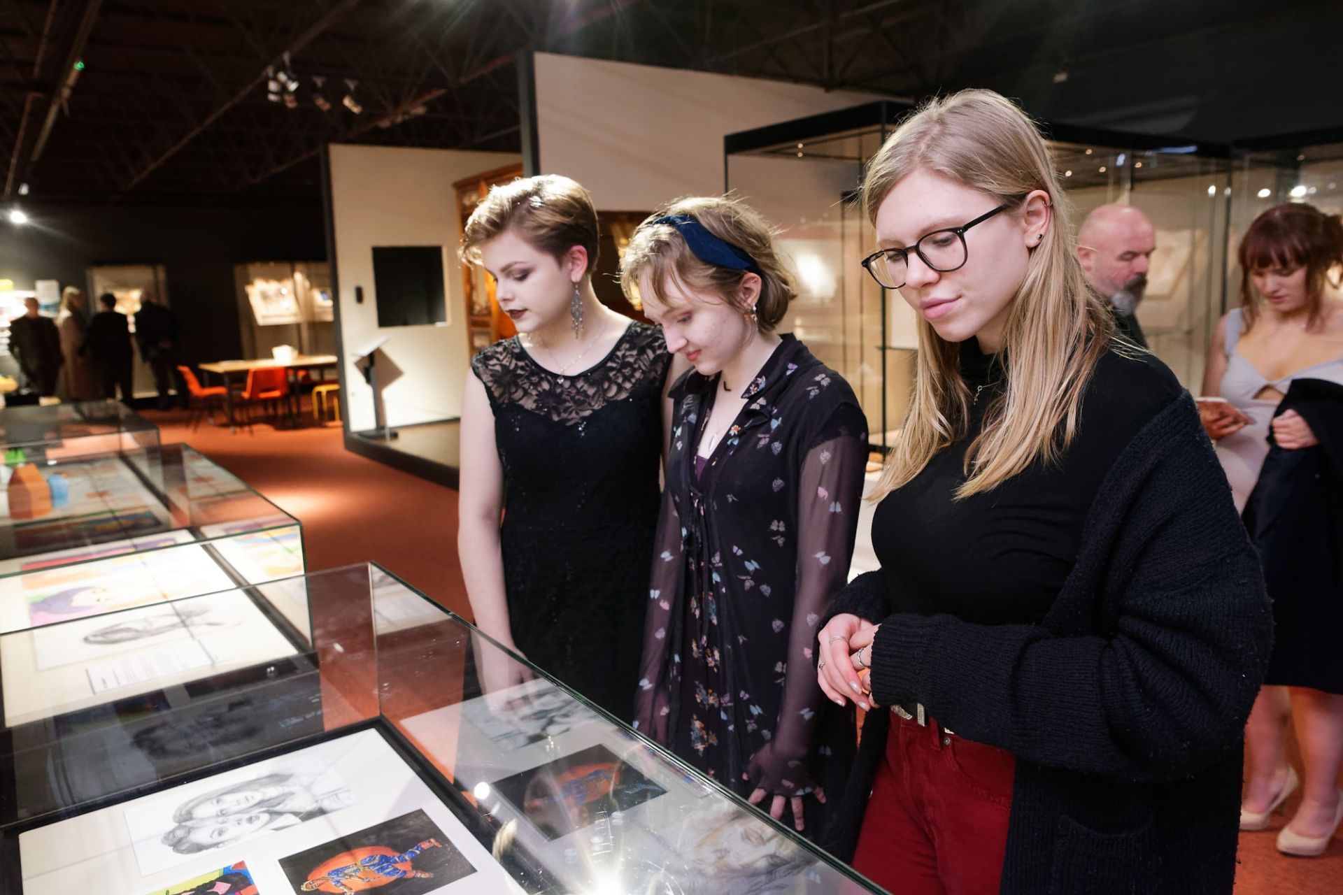 Three visitors to the exhibition exploring the display cabinets