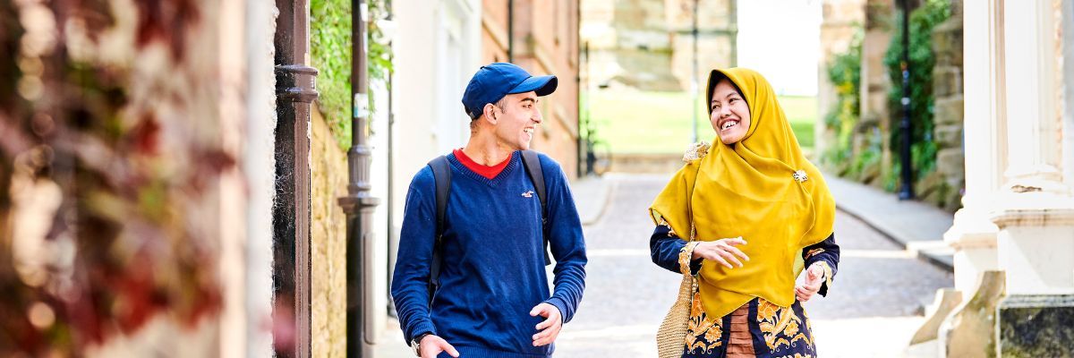 Two students talk as they walk down the cobbled street of Bow Lane, Durham