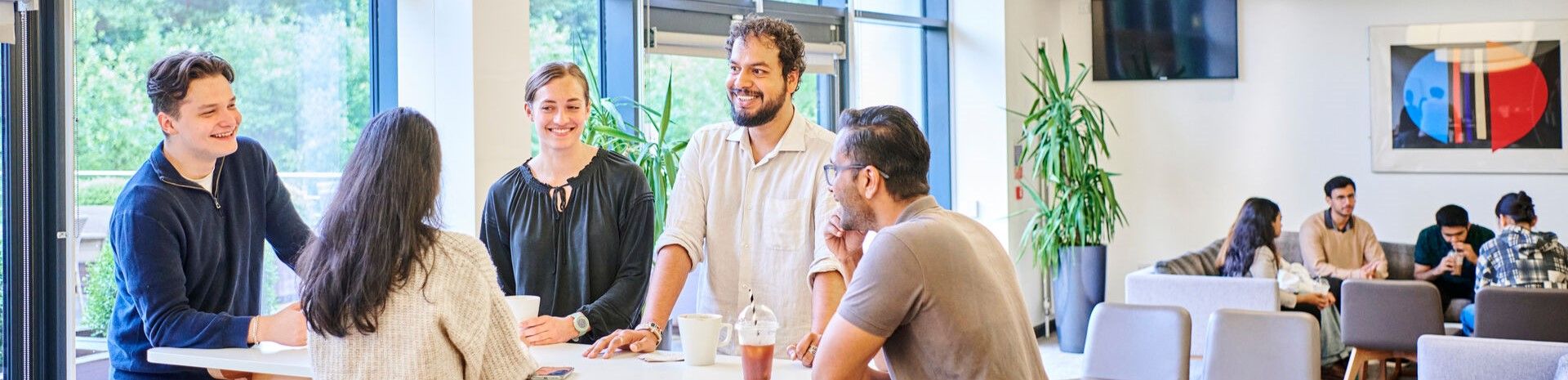 A group of mature students having coffee together in a modern lounge environment