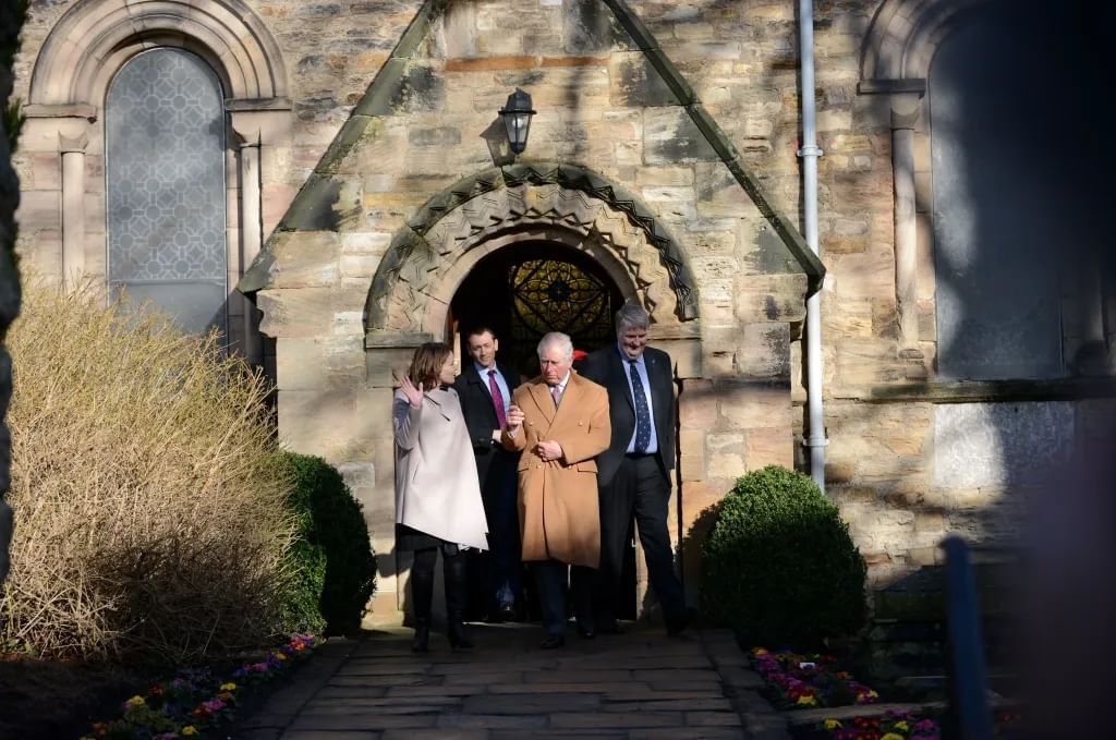 Four people stepping out of a stone chapel