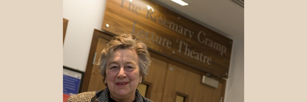 Professor Dame Rosemary Cramp stands in front of sign at the lecture theatre bearing her name