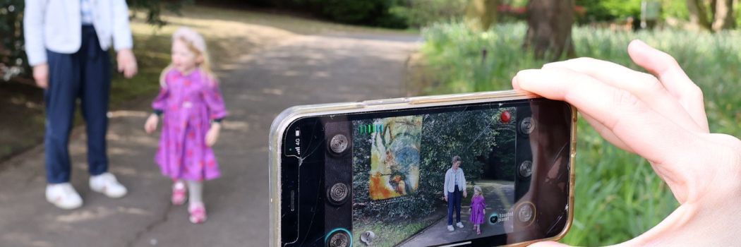 View through a mobile phone screen of a woman and child on a woodland path