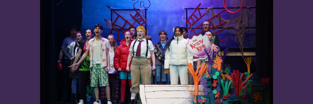 Members of the Durham student theatre stand onstage and sing in a performance