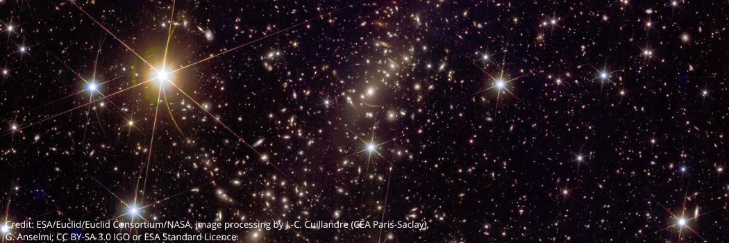 A galaxy cluster showing bright galaxies against a black, starry backdrop