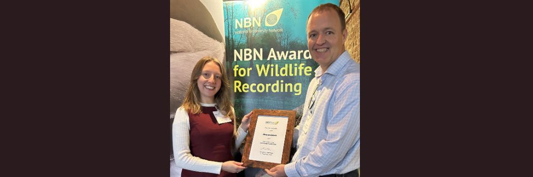 Two people smile at the camera holding a certificate.