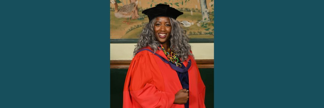 Anne-Marie Imafidon wearing a black academic cap and red robes smiling at the camera.