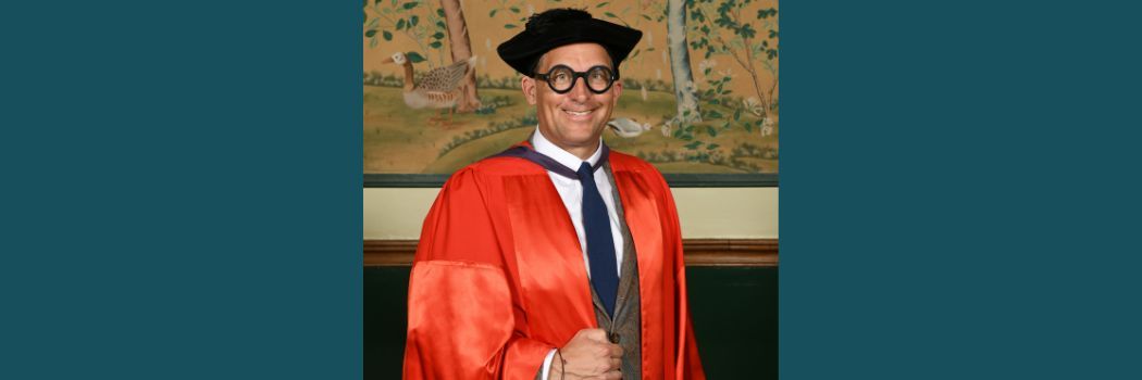 James Timpson wearing a black academic cap and red robes smiling at the camera.