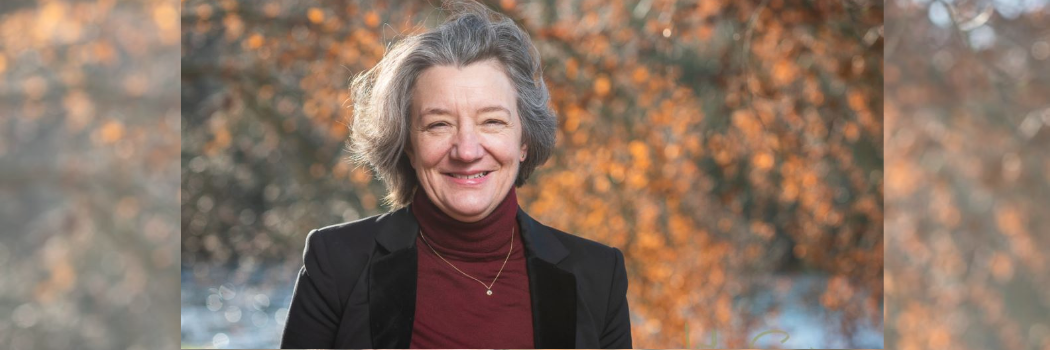 VC Karen O'Brien smiling outdoors with an autumnal tree behind her