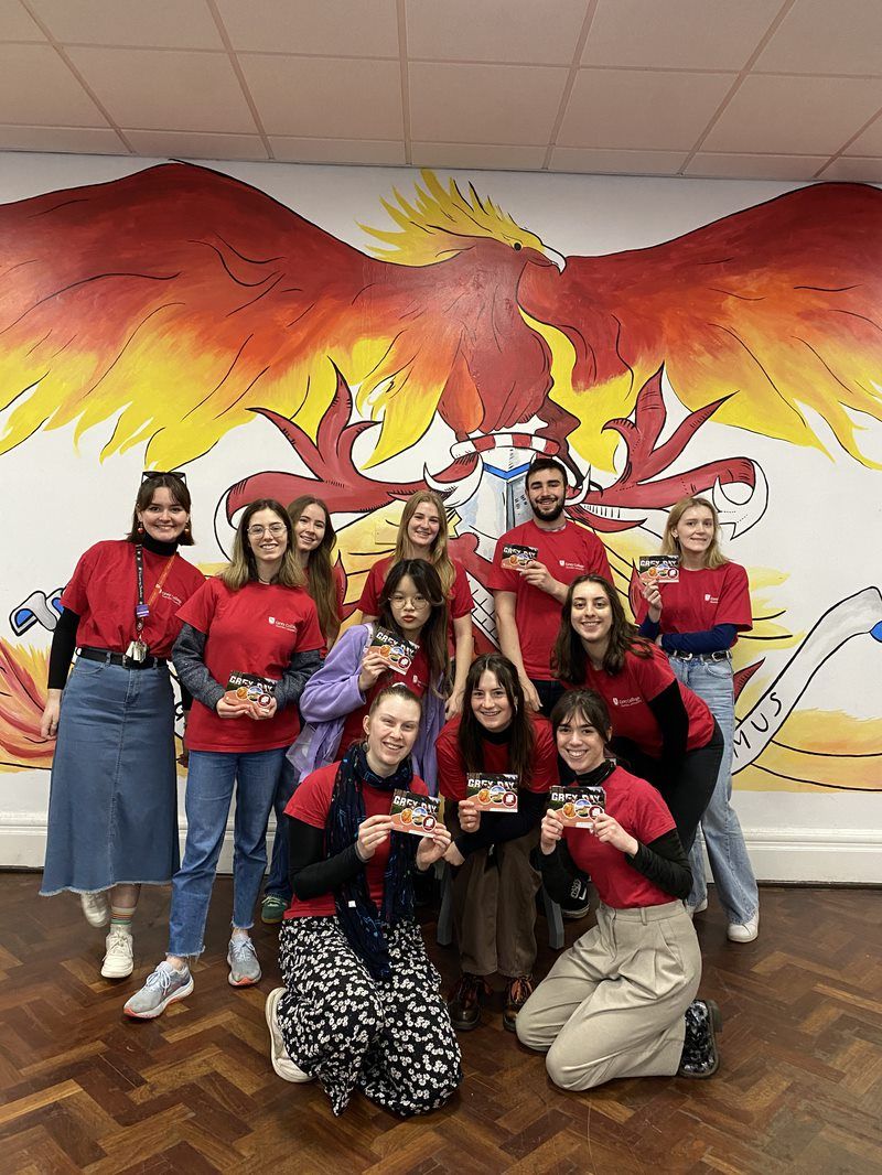 Grey Student Ambassadors in front of a phoenix mural in Junior Common Room