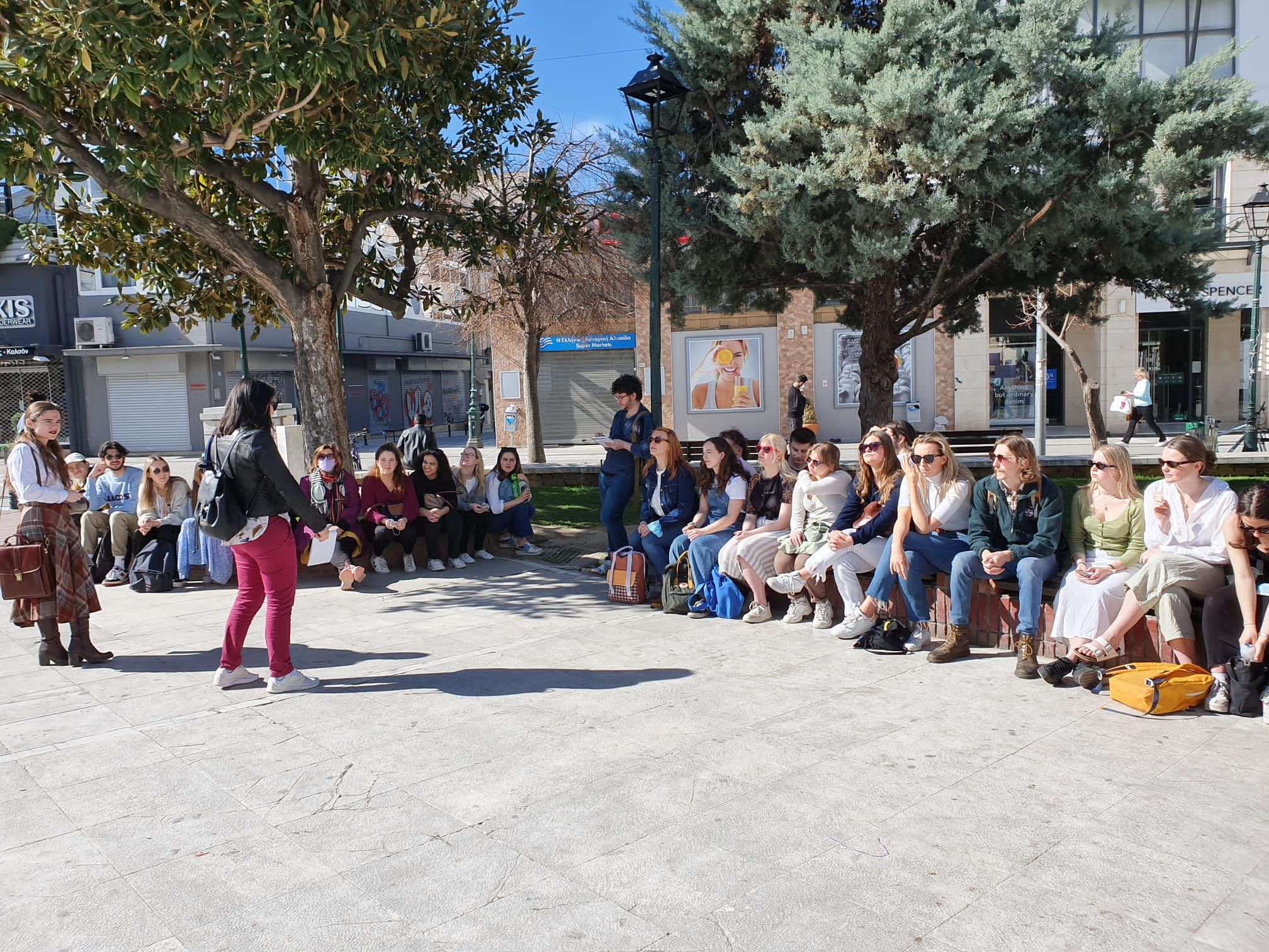 a large group of students sitting in a sunny square