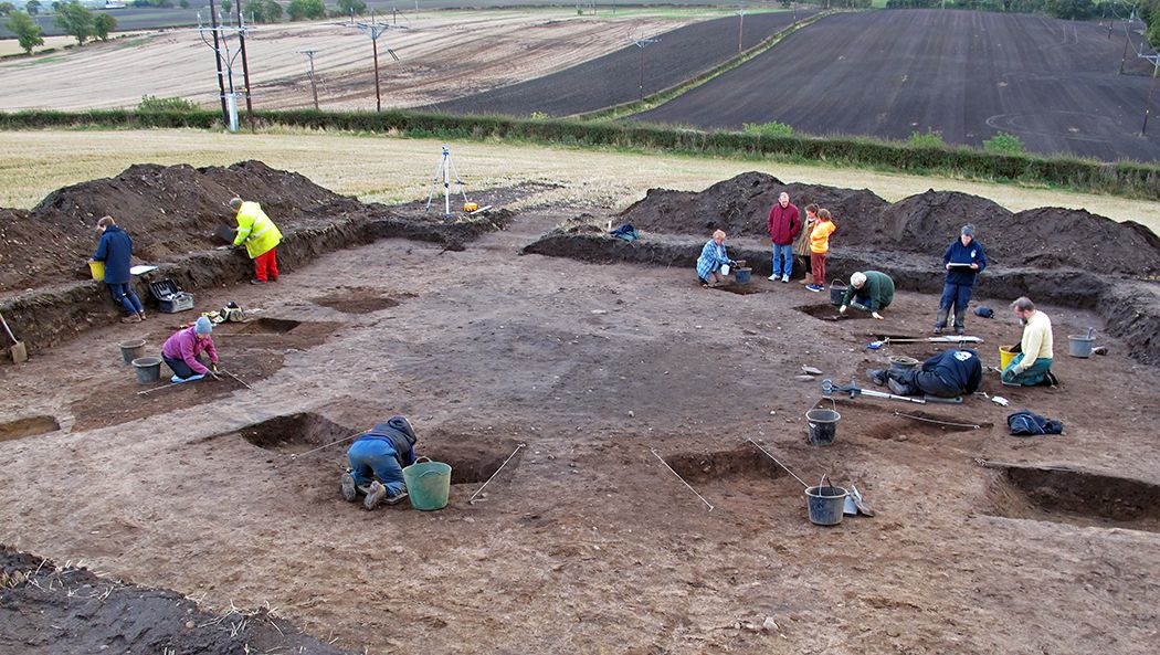 People in a field excavating a circular ditch feature