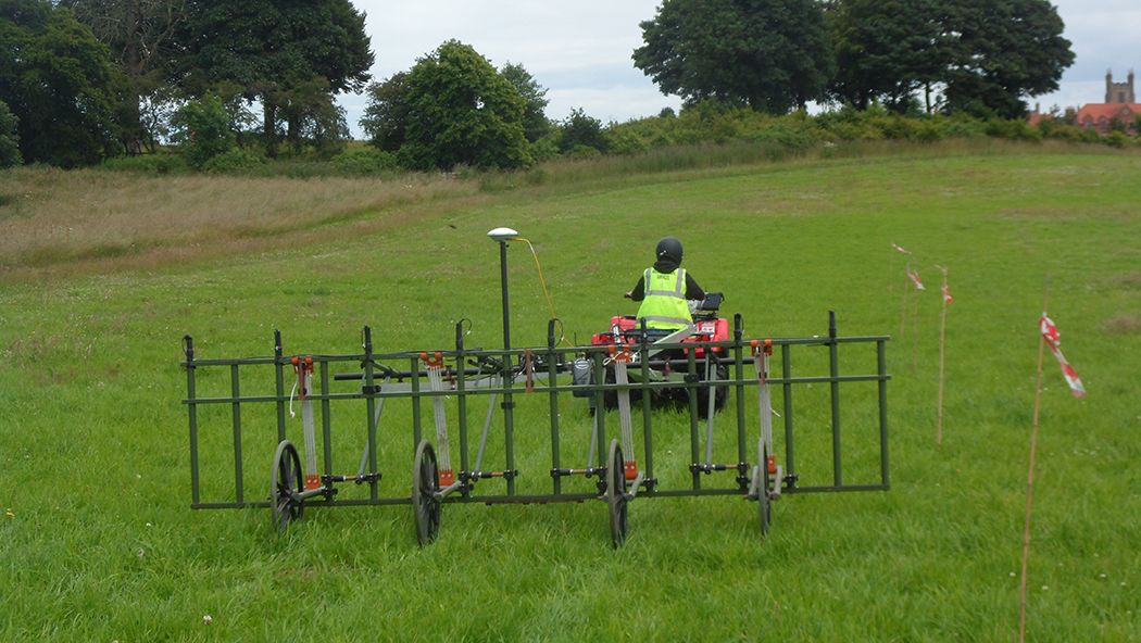 A quadbike pulling a cart-mounted geophysical survey system