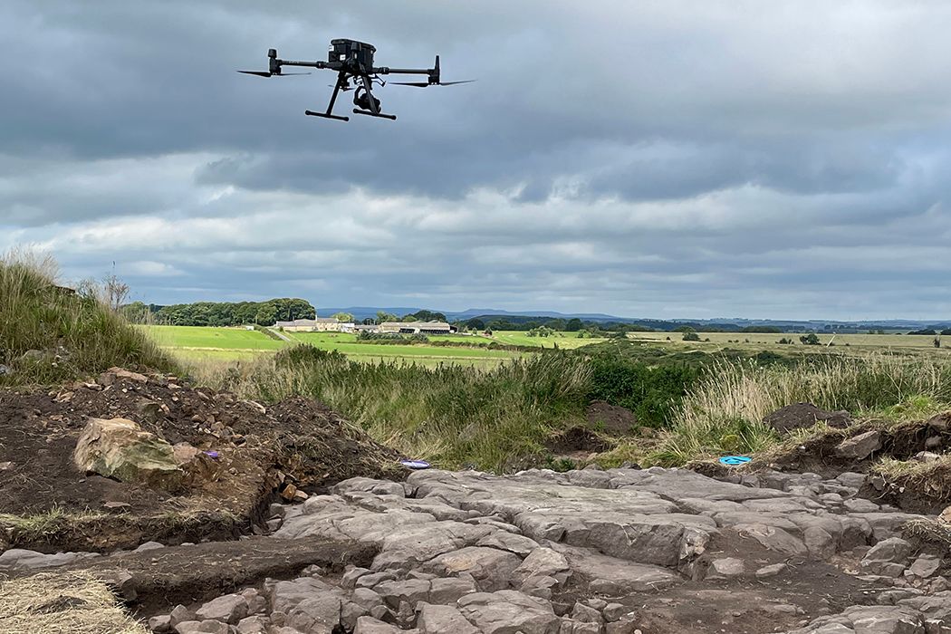 A UAV or drone with a camera flying over an exposed rock which contains rock art