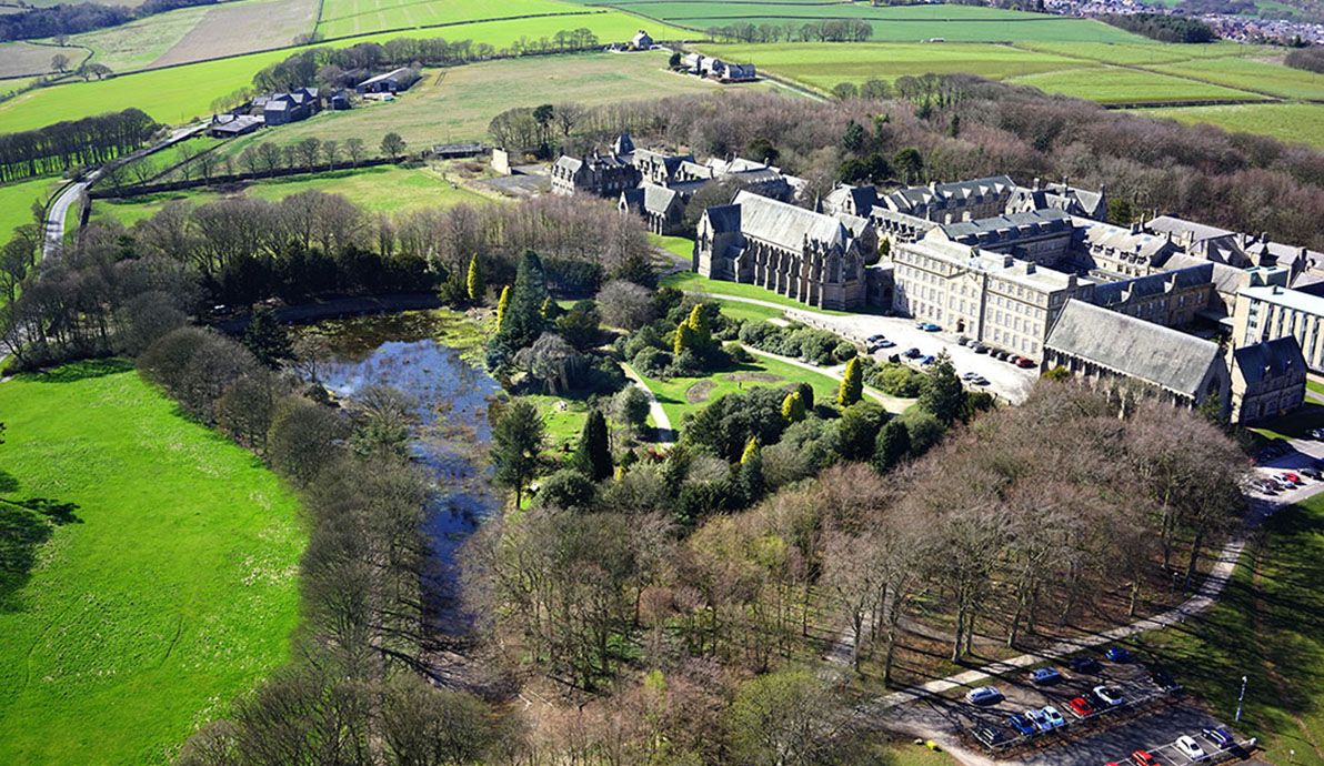 Overhead view from a drone showing historic building on the right and gardens and lake in the centre