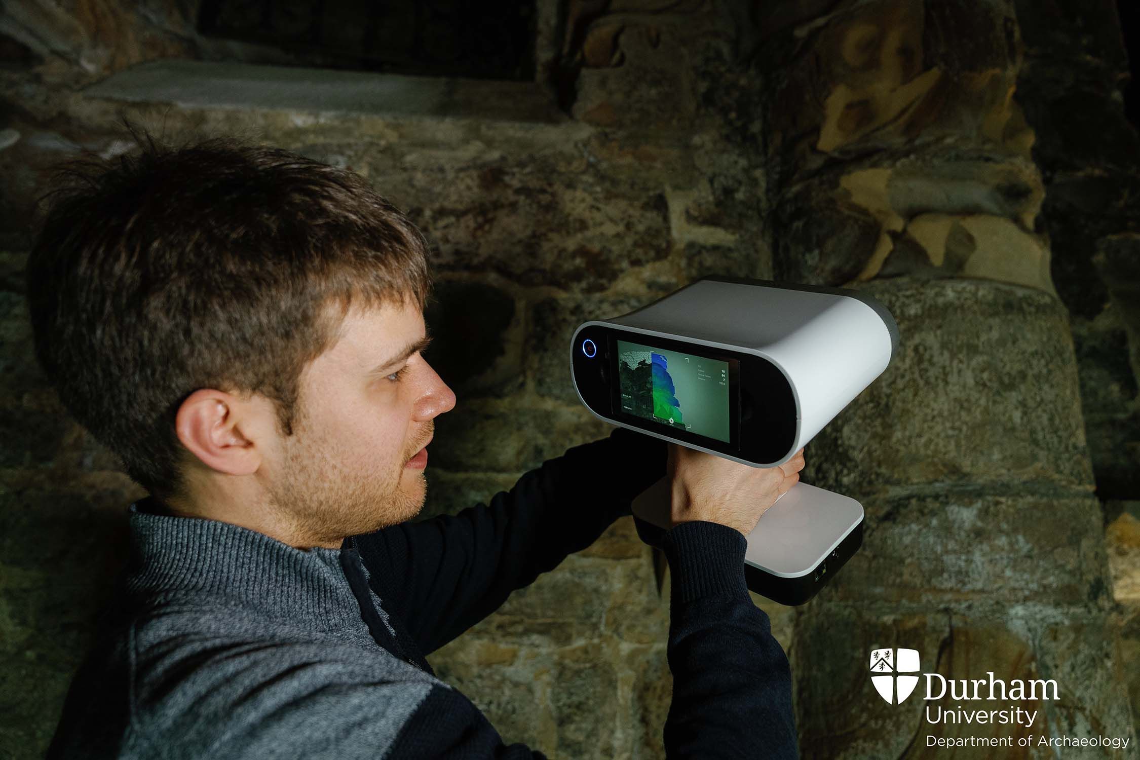 Closer photo of Alexander Jansen holding a laser scanner up to a column in the Norman Chapel.