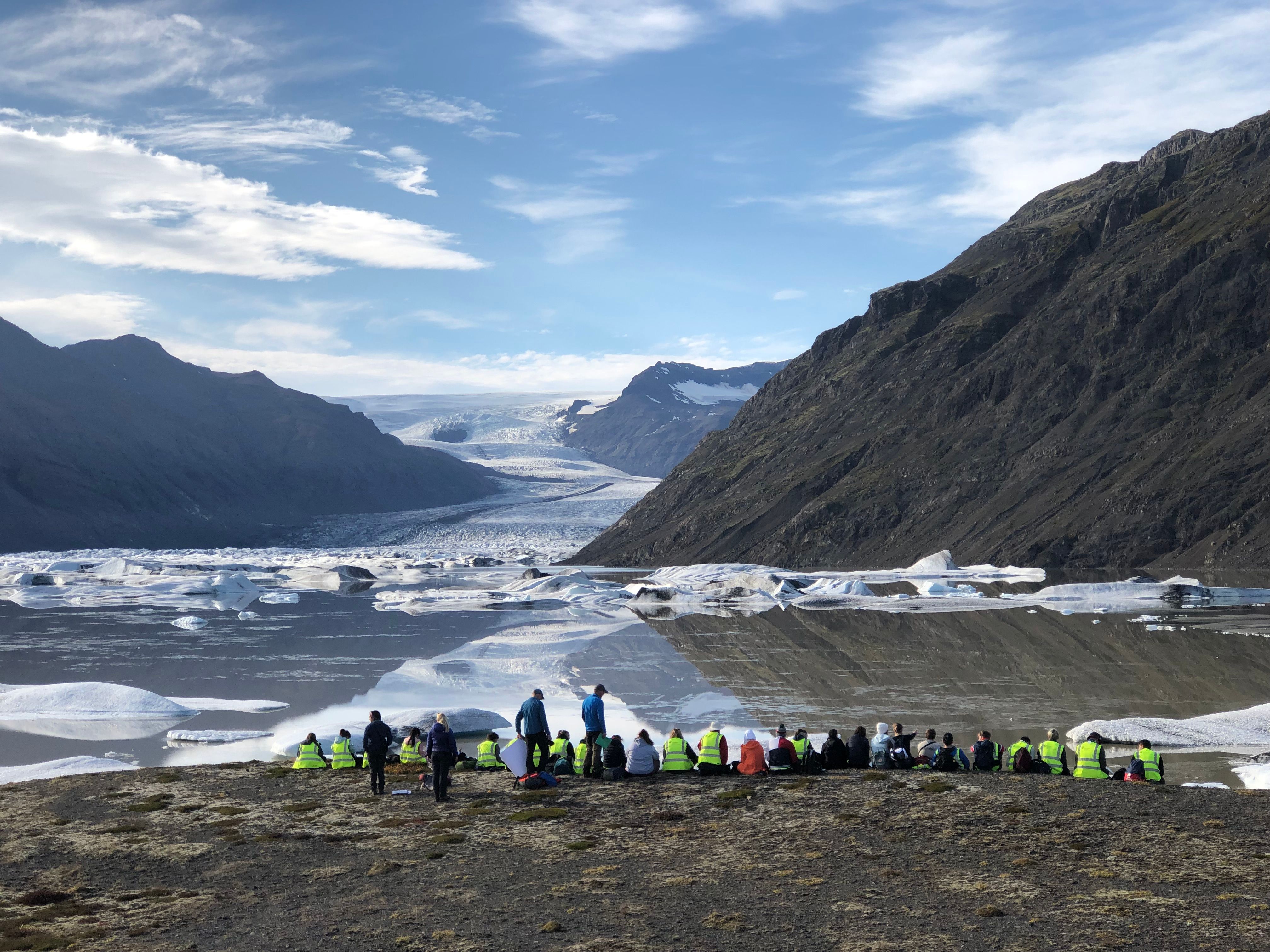 students sitting in the arctic near a glacier