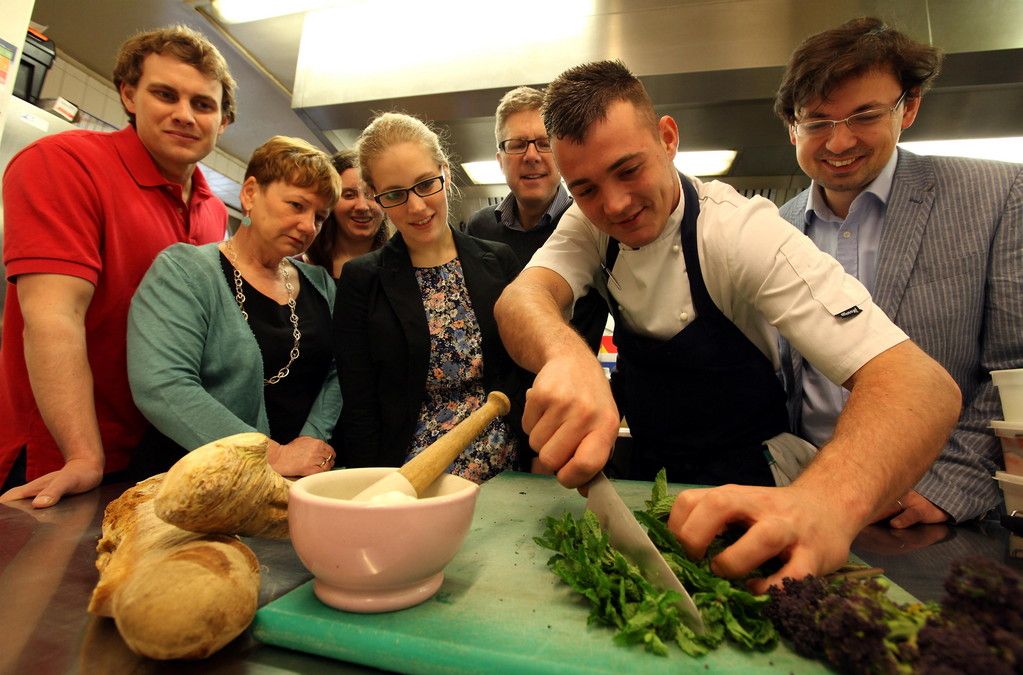 A group of people watch and smile as a man chops food