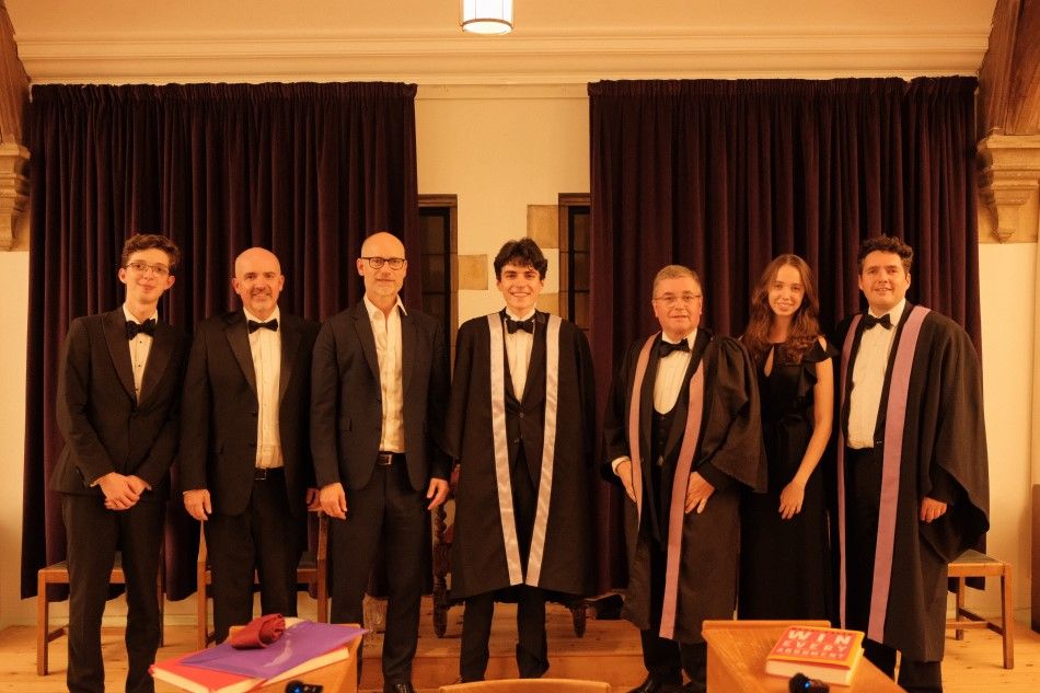 Five people in smart clothes and robes smiling at the camera