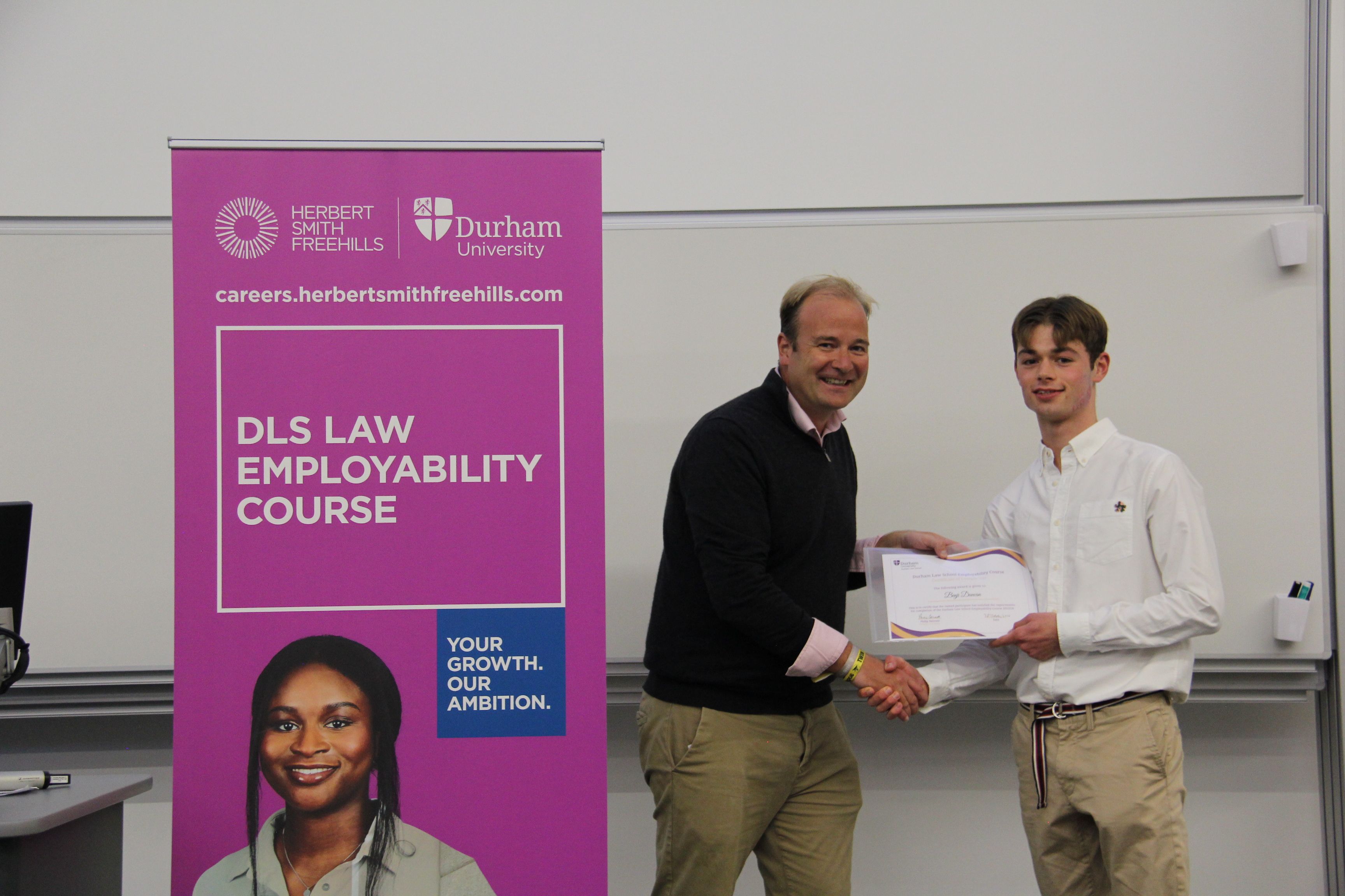 Michael Aherne, Partner, Herbert Smith Freehills presenting Benji Duncan, member of the first team to finish the course, with his 2023/24 Employability Completion of Course Certificate