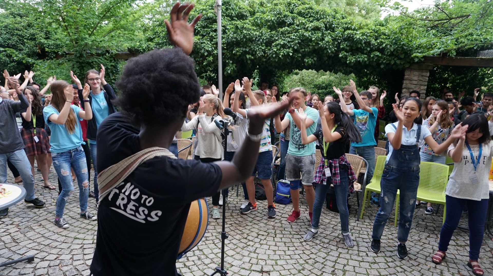 The musician Ezé performing for a group of young people who are clapping along