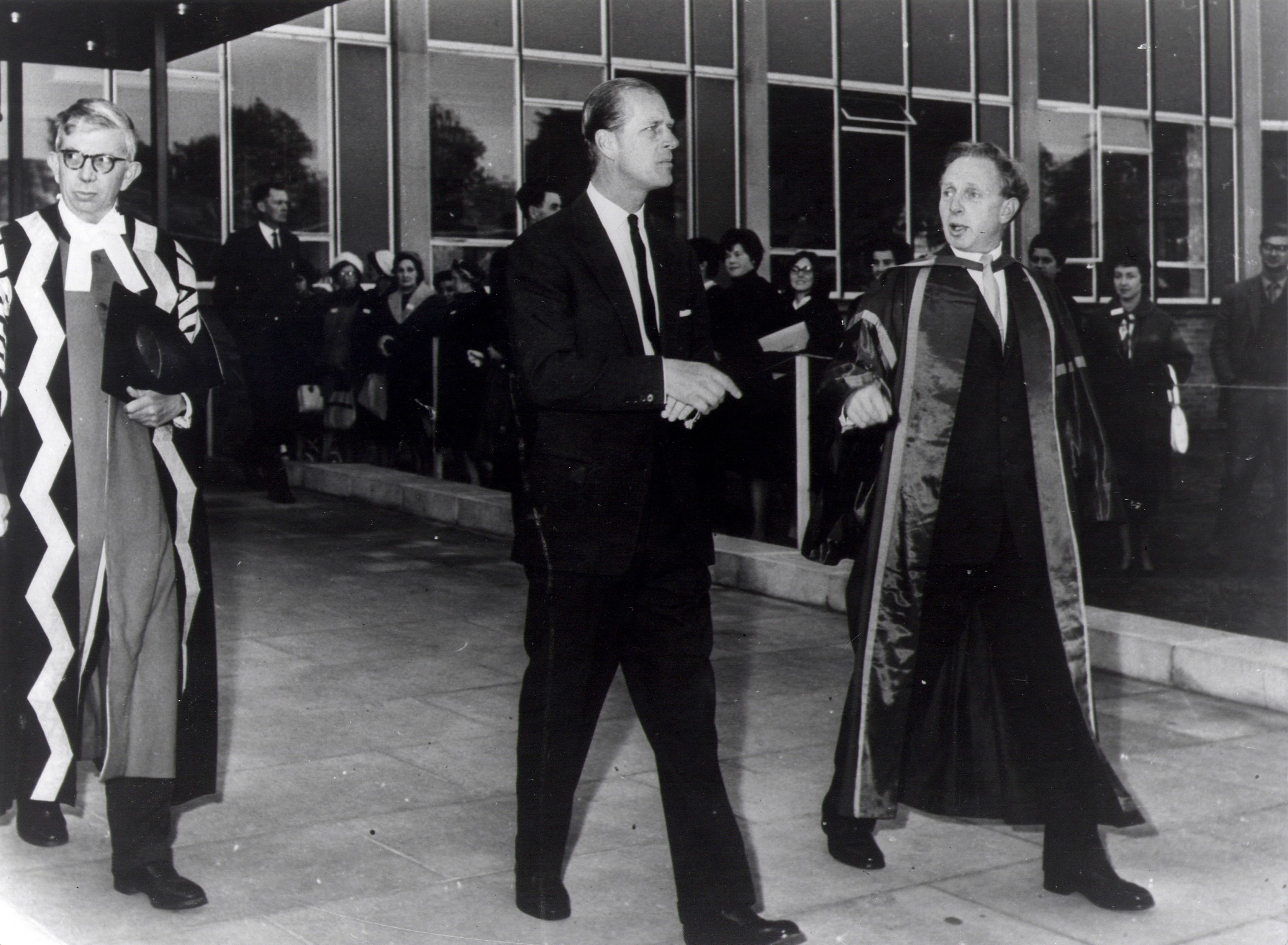 Photo of HRH Prince Philip walking out of the Rochester building entrance with George Rochester