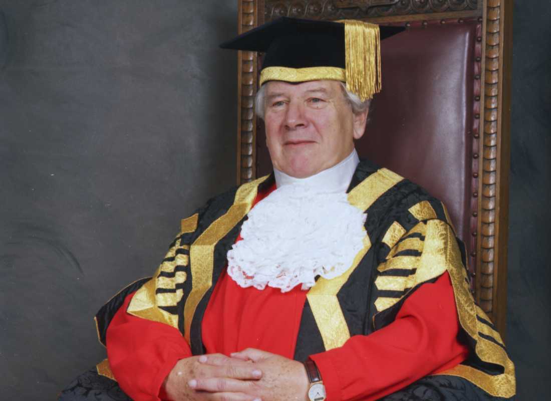 Profile picture of Sir Peter Ustinov in ceremonial robes sat in a high back chair