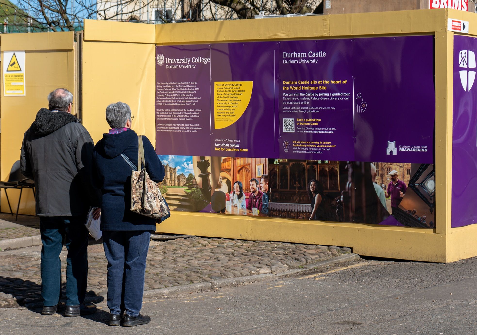 Visitors reading information on the hoardings around the Norman Chapel Project site