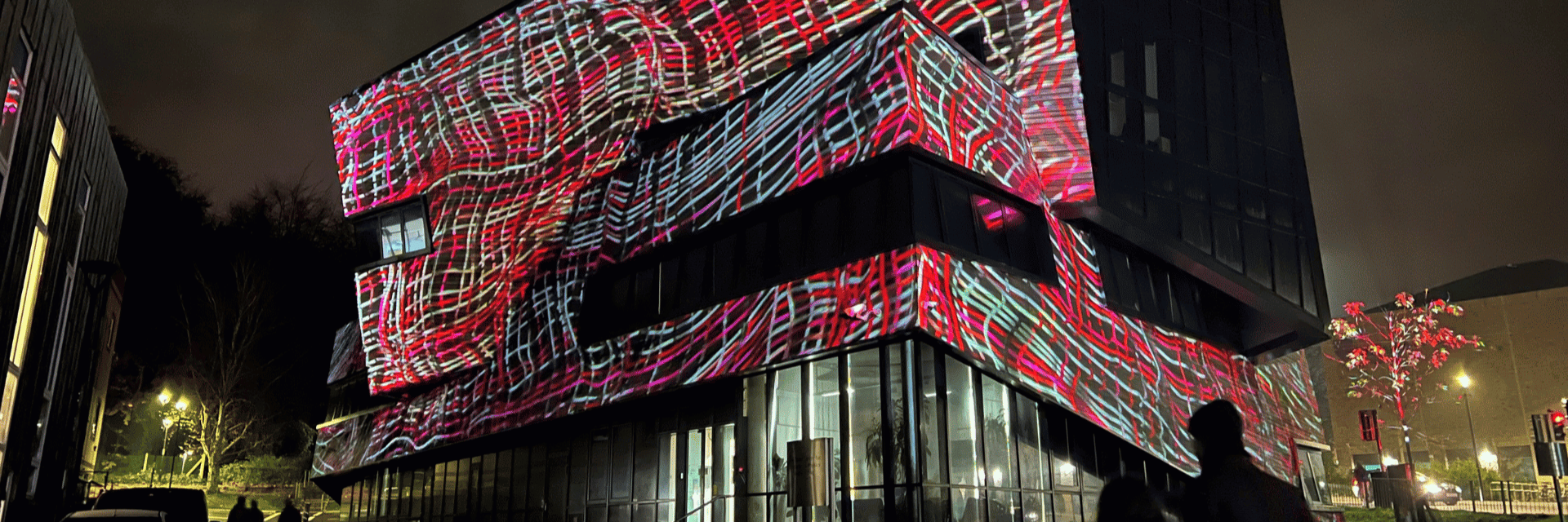 The Ogden Centre at night illuminated by red and pink art