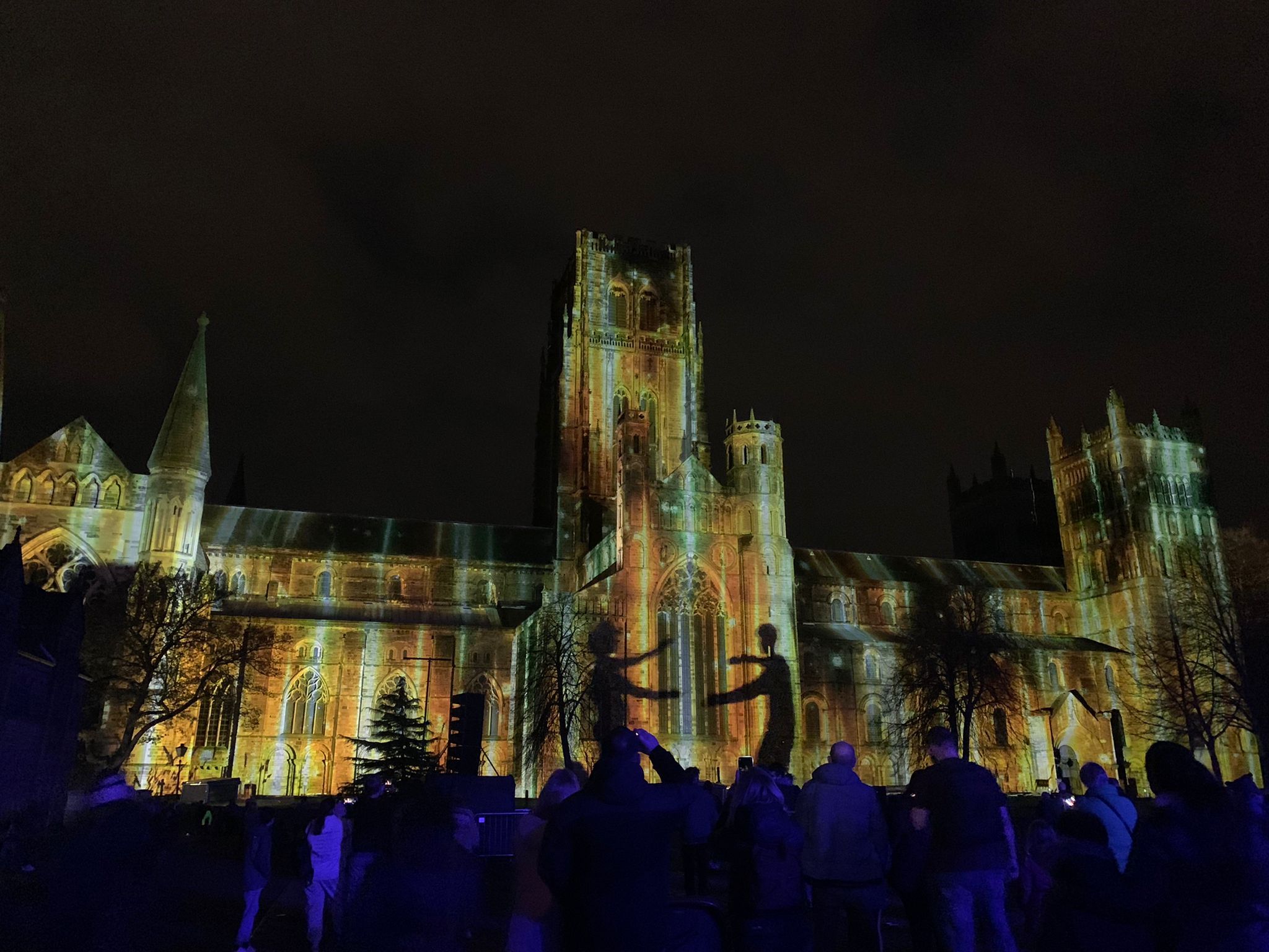 Durham Cathedral illuminated during the Lumiere festival with crowds in the foreground