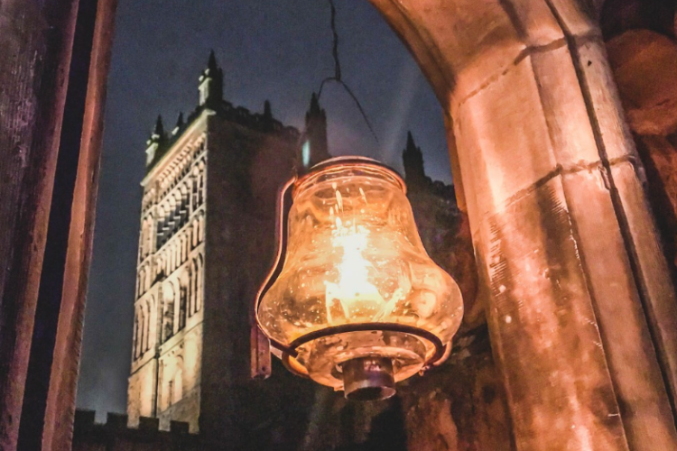 A lantern illuminated in the foreground with a view of Durham Cathedral behind