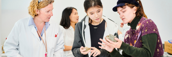 Three Students and Science Professor inspecting a rock