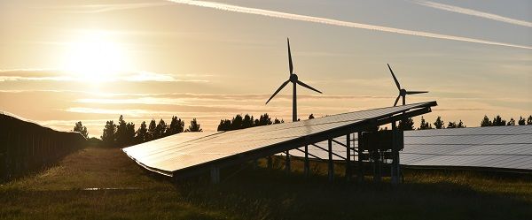 Solar panels in foreground with wind turbine behind