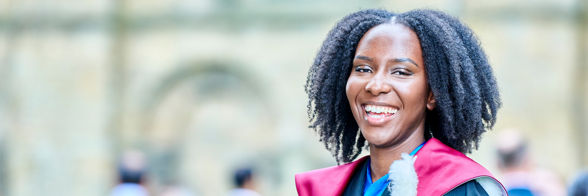 A happy graduate standing in front of Durham Cathedral during a congregation ceremony.