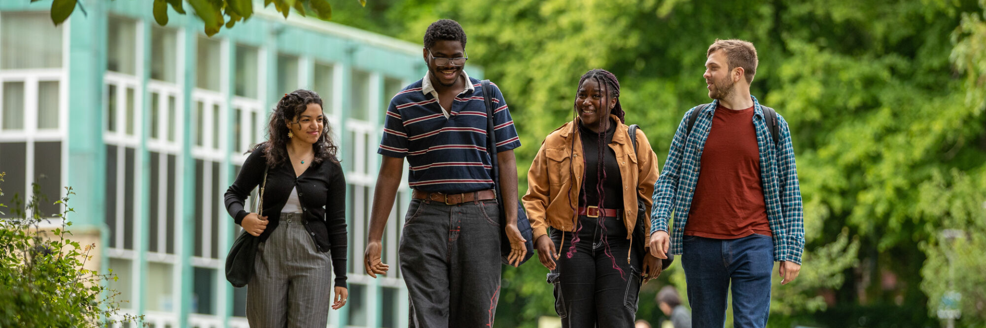 A group of four students walking together. They are talking to each other and smiling.